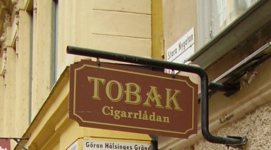Tobak Cigarrlådan : Smidesstativ och plåtskylt i Gamla stan.