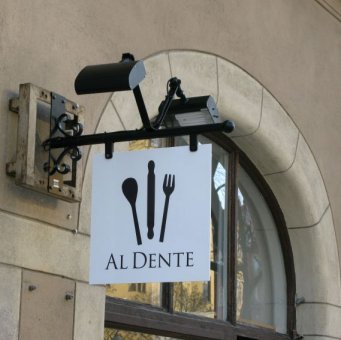 Al Dente: Vi har tillverkat en smidesskylt med PL-strålkastare till Al Dente. Bottenplåten görs av 3mm aluminiumplåt som vitlackeras. Logon i svart vinylfolie.